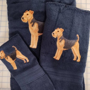 May include: Set of three navy blue towels with embroidered images of brown and black wirehaired terrier dogs.