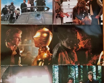 Könnte beinhalten: Ein Satz von acht Filmposter-Stills aus dem Film Die Rückkehr der Jedi-Ritter. Die Stills zeigen verschiedene Charaktere aus dem Film, darunter Luke Skywalker, Darth Vader, Prinzessin Leia, Han Solo, Chewbacca, Yoda und R2-D2. Die Stills sind auf weißem Hintergrund gedruckt, mit dem Filmtitel und Copyright-Informationen am unteren Rand jedes Stills.