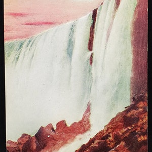 Może przedstawiać: Winietkowa pocztówka przedstawiająca widok Amerykańskich Wodospadów w Niagara Falls. Obraz przedstawia kaskadowe wody spływające z krawędzi wodospadów, z skalistym klifem na pierwszym planie. Niebo jest w delikatnym różowym i niebieskim kolorze.