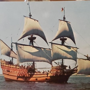 May include: A vintage postcard featuring a detailed illustration of a large, wooden sailing ship with multiple sails. The ship is sailing on a calm body of water with a blue sky and white clouds in the background.