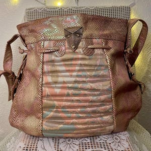 May include: A shoulder bag with a snakeskin pattern in shades of pink, peach, and gold. The bag features a decorative metal clasp and a pleated front panel. It has a shoulder strap and a top handle.