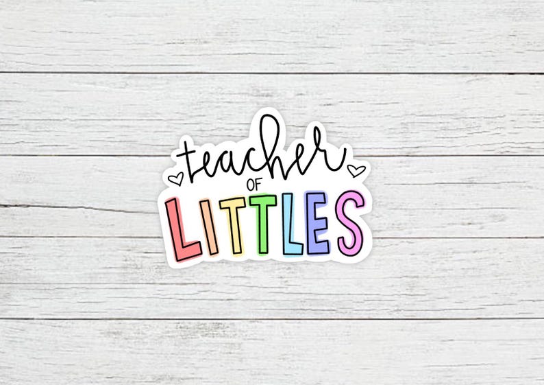 May include: A sticker with the text "teacher of littles" in rainbow colors with hearts on either side of the text.