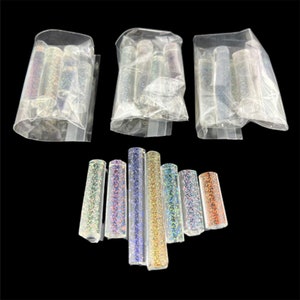 May include: Assortment of iridescent glitter in clear tubes. The glitter is in a variety of colors, including gold, silver, blue, and red. The tubes are packaged in clear plastic bags.