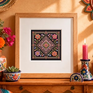 May include: A square framed embroidery piece featuring a central diamond pattern filled with intricate floral motifs in shades of pink, orange, purple, and blue against a black background, encased in a light-toned wooden frame with a white mat.