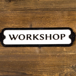 May include: Black and white sign with the word "WORKSHOP" on a wooden background.