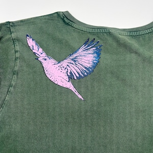 May include: A green t-shirt with a pink and black bird graphic printed on the back.