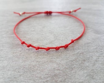 May include: A red string bracelet with small knots throughout.