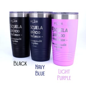 May include: Three stainless steel tumblers in black, navy blue, and light purple. Each features a clear lid, a silver rim, and horizontal ridges at the base. Engraved text reads 2024, 2025, or 2026, Escuela del Servicio de Precursor, and Cumple Completamente Tu Ministerio.