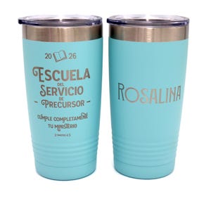 May include: Two light blue stainless steel tumblers with clear lids. The left tumbler features the text 2026, an open book icon, and the words ESCUELA DEL SERVICIO DE PRECURSOR, CUMPLE COMPLETAMENTE TU MINISTERIO, 2 TIMOTEO 4:5. The right tumbler says ROSALINA.