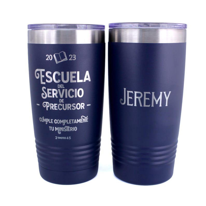 May include: Two dark blue stainless steel tumblers with clear lids. The left tumbler features the text 2023, an open book icon, ESCUELA DEL SERVICIO DE PRECURSOR, CUMPLE COMPLETAMENTE TU MINISTERIO, and 2 TIMOTEO 4:5. The right tumbler features the name JEREMY.