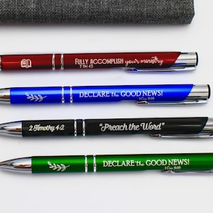 May include: Four pens with different colored bodies and silver accents. Each pen has a different inspirational quote and bible verse engraved on it. The quotes are "FULLY ACCOMPLISH your ministry 2 TIM 4:5", "DECLARE the GOOD NEWS! 1 Cor 9:16", "2 Timothy 4:2", and "DECLARE the GOOD NEWS! 1 Cor 9:16".