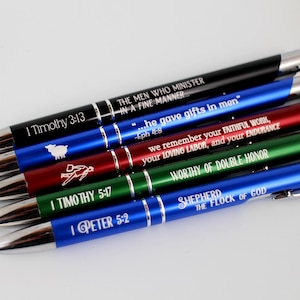 May include: A set of six blue, red, green and black pens with silver accents. Each pen has a different bible verse engraved on it. The verses are: 1 Timothy 3:13, "...he gave gifts in men" -Eph 4:8, "we remember your FAITHFUL WORK, your LOVING LABOR, and your ENDURANCE", "WORTHY OF DOUBLE HONOR", 1 Timothy 5:17, and 1 Peter 5:2. The last pen has "SHEPHERD THE FLOCK OF GOD" engraved on it.