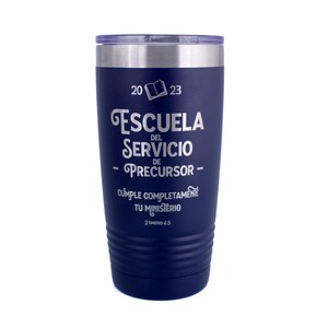 May include: A dark blue stainless steel tumbler with a clear lid. The front features white engraved text reading 2023, an open book icon, ESCUELA DEL SERVICIO DE PRECURSOR, CUMPLE COMPLETAMENTE TU MINISTERIO, and the scripture reference 2 TIMOTEO 4:5.