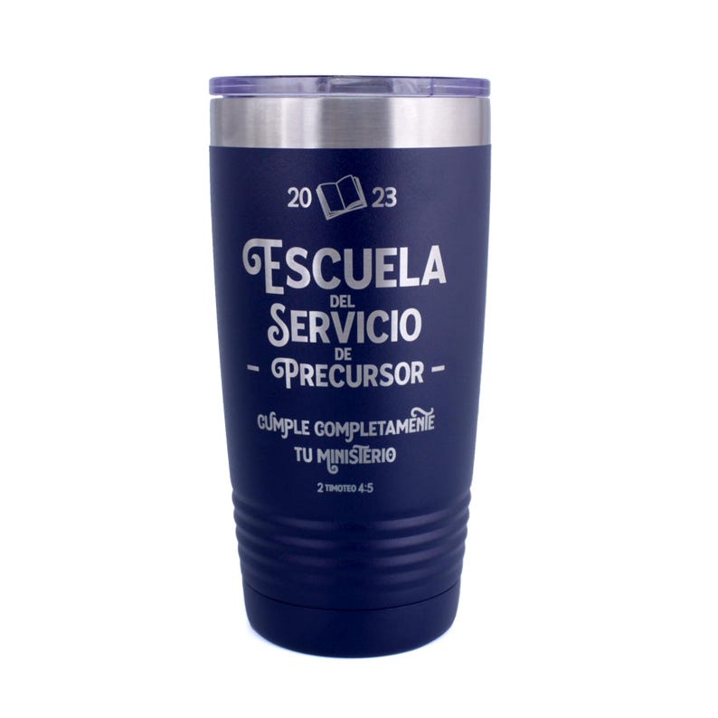 May include: A dark blue stainless steel tumbler with a clear lid. The front features white engraved text reading 2023, an open book icon, ESCUELA DEL SERVICIO DE PRECURSOR, CUMPLE COMPLETAMENTE TU MINISTERIO, and the scripture reference 2 TIMOTEO 4:5.