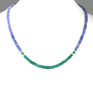 May include: A gemstone necklace featuring a gradient of blue and green beads. The necklace has a central section of green beads, transitioning to blue beads on each side. Small gold accents separate the colors. The necklace is displayed on a white mannequin.