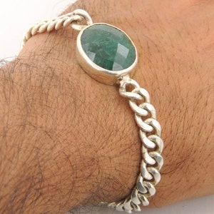 May include: A silver chain bracelet with a large, round, green gemstone.