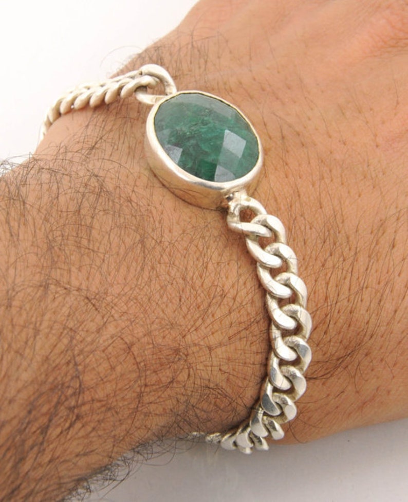May include: A silver chain bracelet with a large, round, green gemstone.
