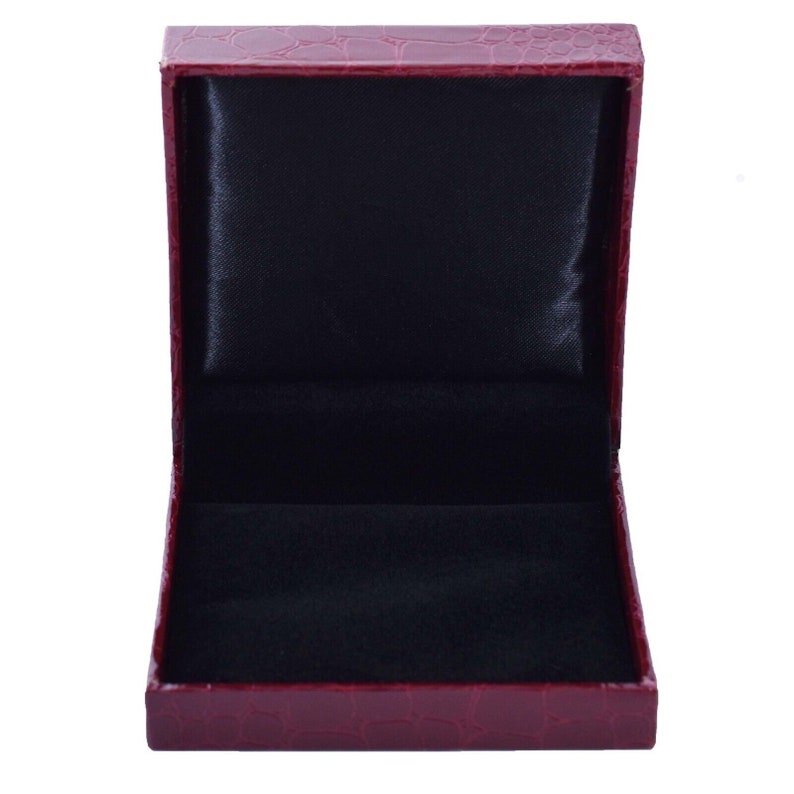 May include: A red faux leather jewelry box with a black velvet interior. The box is open and empty.