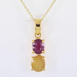 May include: A gold pendant necklace with two gemstones. The top gemstone is a red ruby and the bottom gemstone is a yellow sapphire.