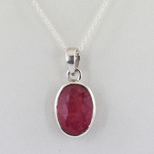May include: A silver chain necklace with a pendant featuring a red oval gemstone.