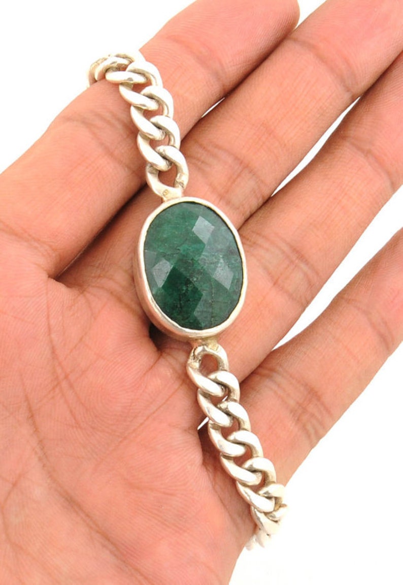May include: A silver chain bracelet with a large, oval-shaped green gemstone.