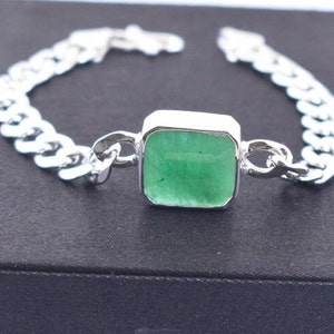 Peut inclure: Un bracelet en argent avec un pendentif carré en pierre verte.