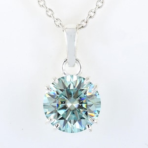 Puede incluir: Un collar de cadena de plata con un colgante que presenta una gran gema redonda de color azul claro con un corte facetado.