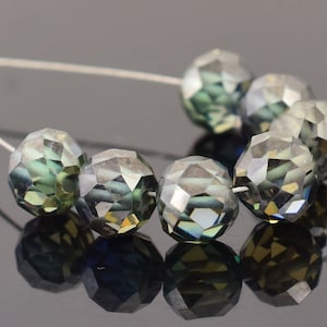 May include: A strand of dark green and blue faceted glass beads. The beads are round and have a faceted design. The beads are strung on a silver wire.