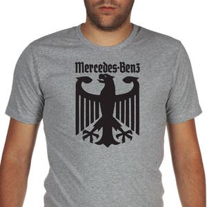 May include: A gray t-shirt with a black German eagle and the text "Mercedes-Benz" printed on the front.