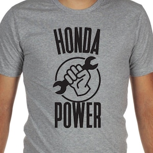May include: A grey t-shirt with a black graphic of a fist holding a spanner inside a circle. The text "HONDA POWER" is printed below the graphic.