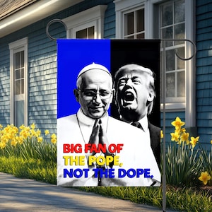 May include: A garden flag with a split design, showing the Pope on the left and Donald Trump on the right. The flag displays the text "BIG FAN OF THE POPE, NOT THE DOPE" in red, yellow, and blue.