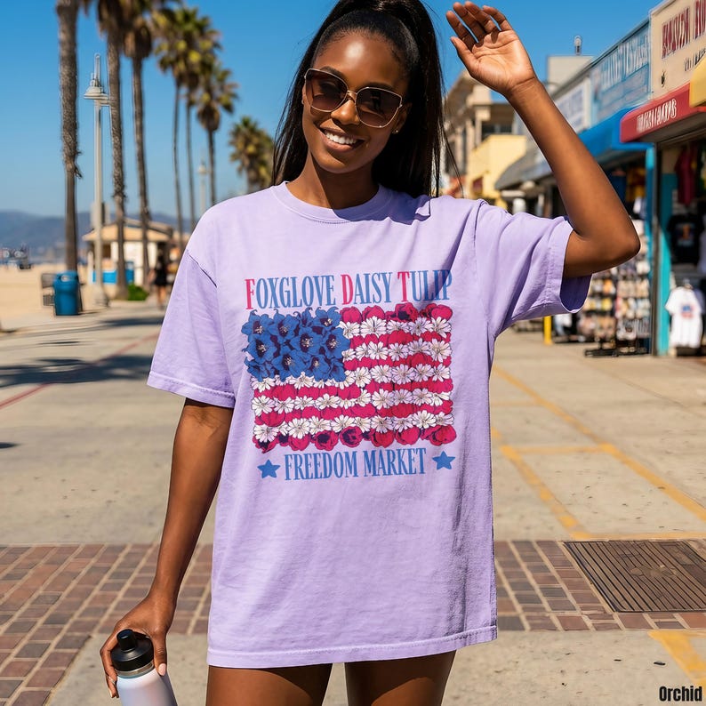 Lavender t-shirt with red, white, and blue floral American flag design.