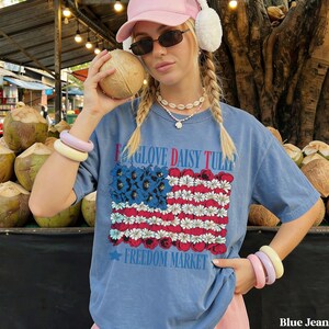 Woman in blue t-shirt with floral American flag design and "Freedom Market" text.