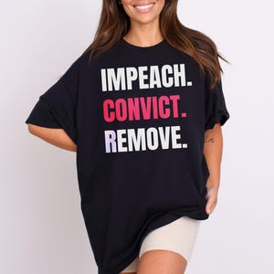 May include: Black oversized t-shirt with the text "IMPEACH. CONVICT. REMOVE." printed in white, pink, and purple.