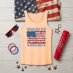 Peach tank top with floral American flag design and "Foxglove Daisy Tulip Freedom Market" text.