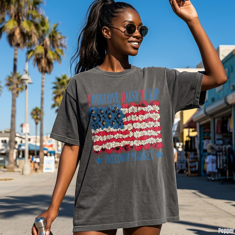 Dark gray t-shirt with American flag made of flowers, "Foxglove Daisy Tulip Freedom Market" text.