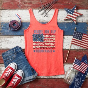 Coral tank top with a flag design of flowers, red shoes, denim shorts, and patriotic decorations.