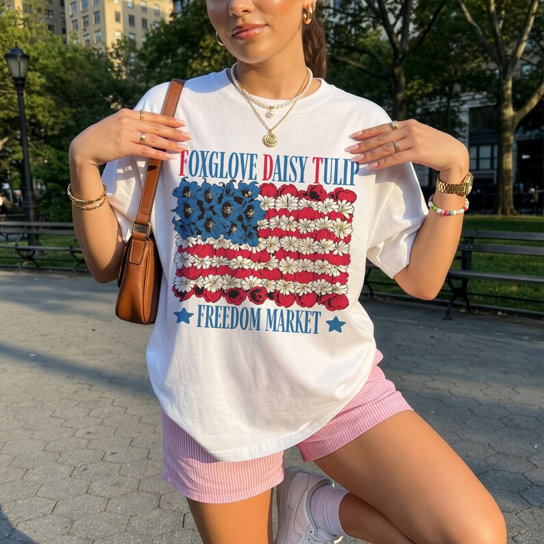 White t-shirt with American flag made of daisies, text "Foxglove Daisy Tulip Freedom Market".