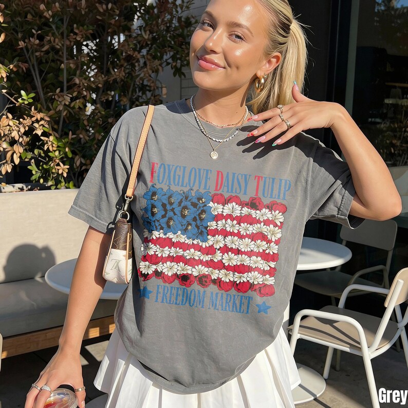 Woman wearing a grey t-shirt with a floral American flag design and "Freedom Market" text.