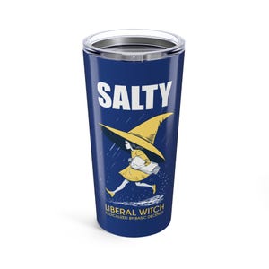 May include: A navy blue tumbler with a silver lid features the word "SALTY" in white. Below, a cartoon witch in a yellow dress and hat runs with a book. The text "LIBERAL WITCH Radicalized by Basic Decency" is printed below the witch.