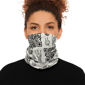 May include: A white neck gaiter featuring black QR codes and peace sign hand gestures. The neck gaiter is worn by a person with dark hair and a black shirt. The background is white.