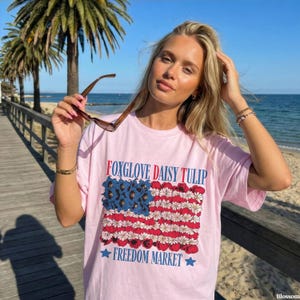 Pink t-shirt with floral American flag design and text.