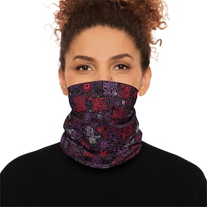 May include: A purple and red patterned neck gaiter. The gaiter features a geometric design with squares and rectangles in shades of purple, red, and white. The person is wearing a black shirt.