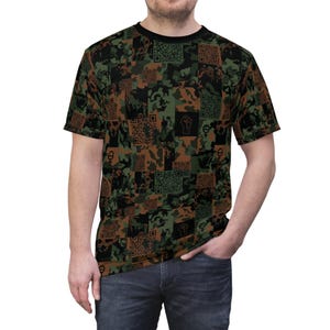 Puede incluir: Una camiseta de manga corta con un estampado de camuflaje en tonos verdes, marrones y negros. El diseño incorpora códigos QR y varios símbolos, incluyendo un puño en alto y el símbolo femenino. La camiseta tiene cuello redondo negro.