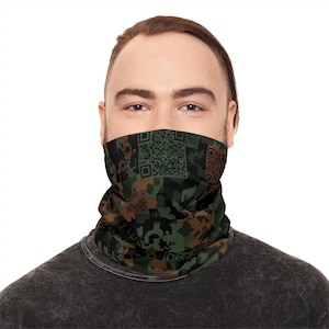 May include: A camouflage-patterned face covering with a mix of green, brown, and black hues. The design incorporates QR codes within the camouflage pattern. The face covering is worn around the neck and covers the lower face.