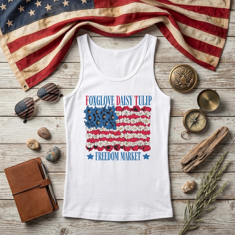 White tank top with American flag design featuring "Foxglove Daisy Tulip" and "Freedom Market".