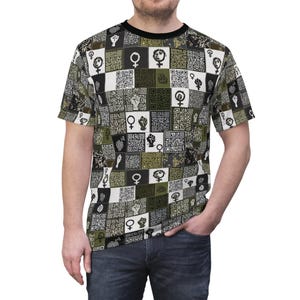 Puede incluir: Una camiseta de manga corta con cuello negro. Presenta un patrón repetido de códigos QR, símbolos femeninos y puños en alto en tonos negro, blanco y verde oliva. La camiseta la lleva una persona.