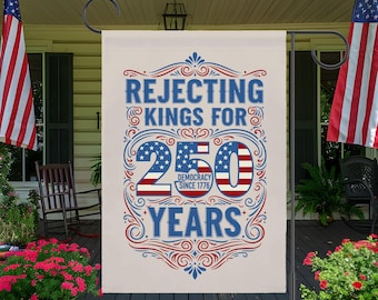May include: A cream-colored garden flag with the text "Rejecting Kings For 250 Years" in blue and red. The number 250 is stylized with the American flag design. The flag is displayed on a black metal stand, with American flags in the background.