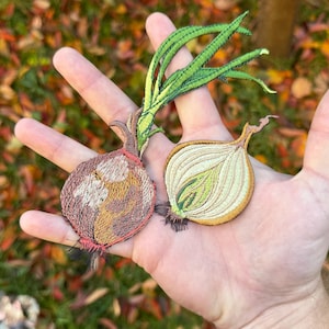 May include: Two embroidered iron-on patches of onions. One is a red onion with a green stem and the other is a white onion with a green stem.