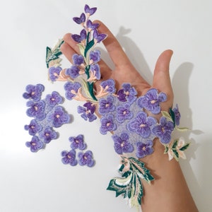 May include: Purple and green embroidered flower appliques. The appliques are in the shape of flowers and leaves. They are perfect for adding a touch of elegance to any project.